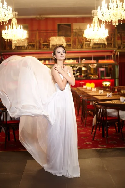 Beautiful bride in flying wedding dress in the restaurant — Stock Photo, Image