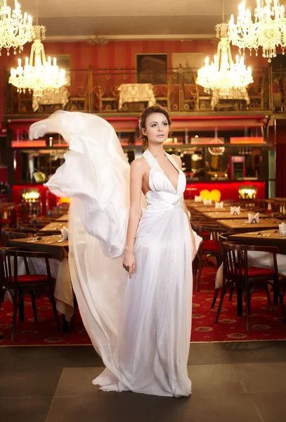 Mooie bruid vliegen trouwjurk in het restaurant — Stockfoto