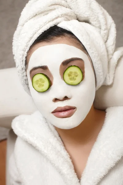 Chinese vrouw met komkommer en gezichtsmasker — Stockfoto
