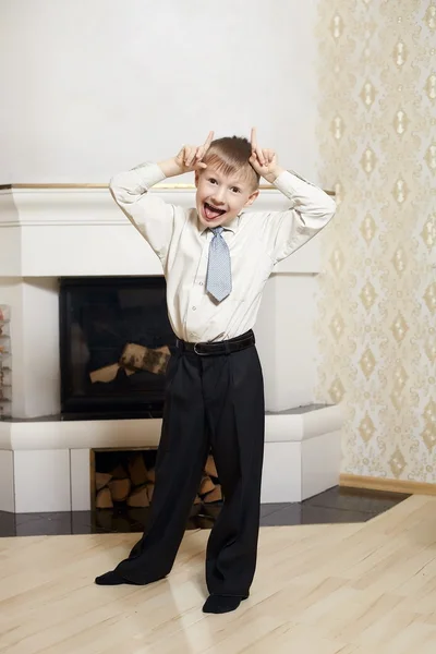 Portrét legrační malého chlapce, stojící nedaleko firepleace doma v nákladech — Stock fotografie