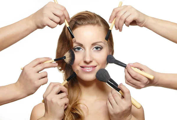 Muchas manos se aplican maquillaje en los cepillos de maquillaje de la mujer —  Fotos de Stock