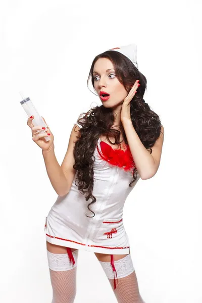 Сексуально красивая удивленная брюнетка-врач с большим шприцем красного цвета задерживается — стоковое фото