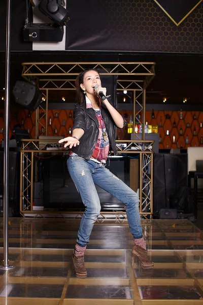 Unga vackra roliga pop stjärna sångare med mikrofon som sitter på scenen i Klubben — Stockfoto