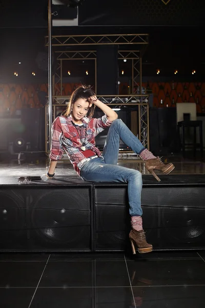 Jovem beautifu engraçado pop star cantor com microfone sentado em cena no clube — Fotografia de Stock