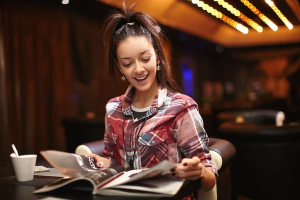 stock image Pretty thinking young woman sitting in the cafe read magazine with a cup of tea