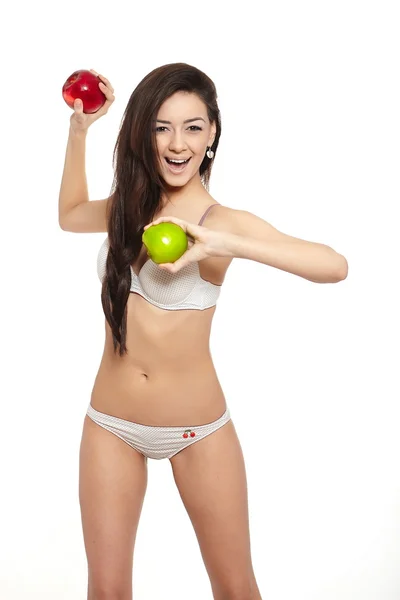 Porträtt av vackra leende brunett kvinna i vita underkläder kasta gröna och röda apple kost isolerad på vit — Stockfoto
