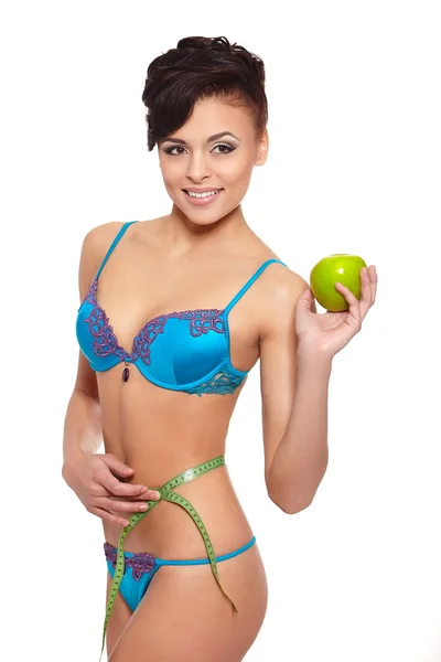 Portrait of beautiful smiling brunette woman in white lingerie with green apple measuring perfect shape isolated on white — Stock Photo, Image