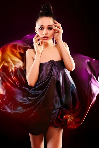 Sensual fashion portrait of beautiful sexy brunette girl model posing in bright colorful flying dress, birght makeup isolated in black background — Stock Photo, Image