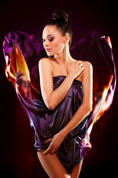 Sensual fashion portrait of beautiful sexy brunette girl model posing in bright colorful flying dress, birght makeup isolated in black background — Stock Photo, Image
