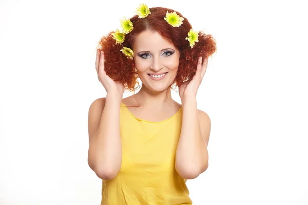 Portrait of beautiful smiling redhead ginger woman in yellow cloth with yellow pink colorful flowers in hair isolated on white holding flowers — Stock Photo, Image