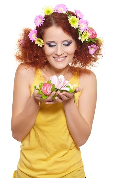 Portrait of beautiful smiling redhead ginger woman in yellow cloth with yellow pink colorful flowers in hair isolated on white holding flowers — Stock Photo, Image