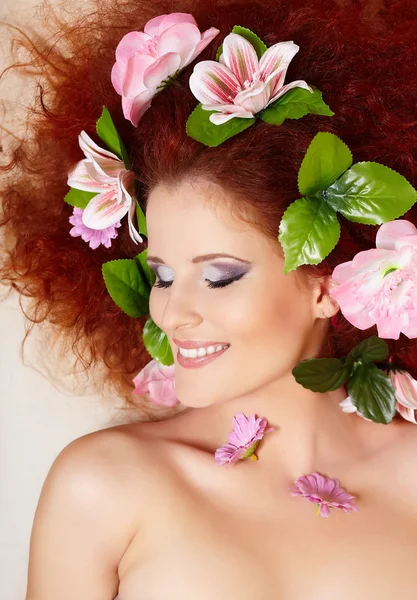 Closeup πορτρέτο του όμορφη κοκκινομάλλα τζίντζερ γυναίκα του χαμόγελου με τα ζωηρόχρωμα λουλούδια στα μαλλιά, στο porofile — Φωτογραφία Αρχείου