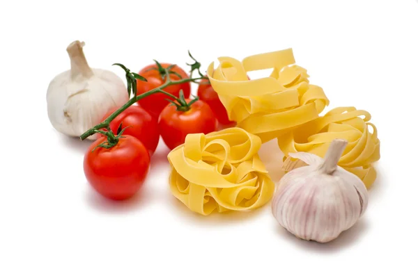 Tomaatit, valkosipuli ja fettuccini valkoisella pohjalla — kuvapankkivalokuva