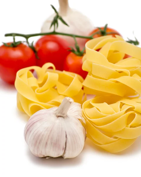 Tomaatit, valkosipuli ja fettuccini valkoisella pohjalla — kuvapankkivalokuva