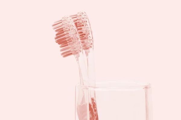 Two toothbrushes in a glass on a red background — Stock Photo, Image