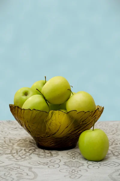 Green apples in a glass vase on the table cloth — Stock Photo, Image
