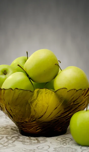 stock image Green apples in a glass vase on the table cloth