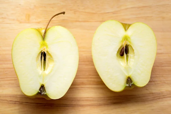 Dwie połówki jabłka na drewnianym stołem — Zdjęcie stockowe