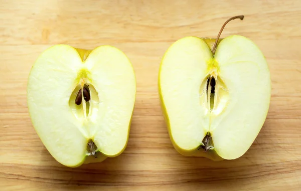 Dwie połówki jabłka na drewnianym stołem — Zdjęcie stockowe