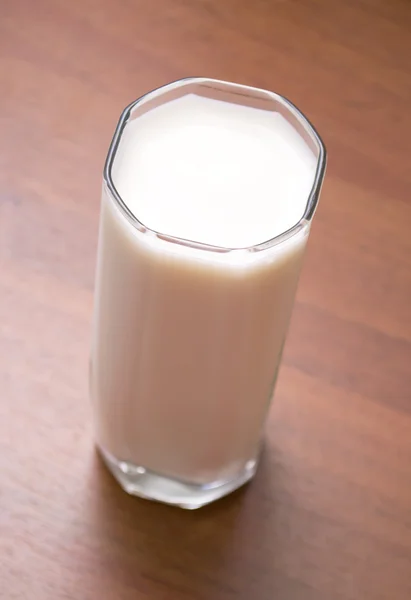 Egy pohár tej a fa asztalon. — Stock Fotó
