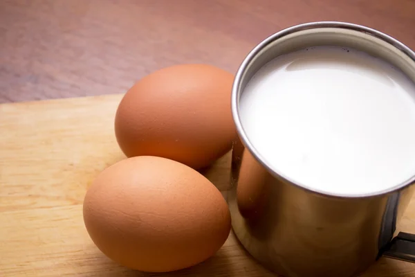 Cup of milk and two eggs — Stock Photo, Image
