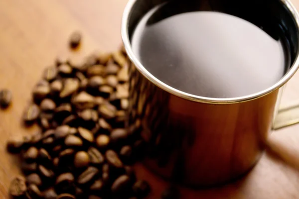 Egy csésze kávé és kávébab egy fa asztalon. — Stock Fotó