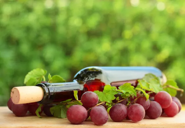 Botella de vino, uva roja y hojas verdes - fondo — Foto de Stock