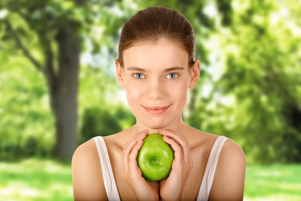 Leende flicka med grönt äpple i trädgården — Stockfoto
