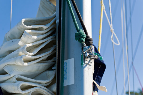 Sailing boat mast with mainsail and spinnaker halyard ropes close up