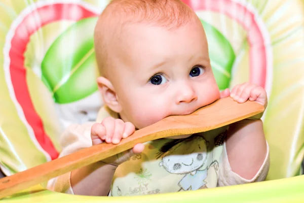 Μωρό δαγκώνει ένα ξύλινο κουτάλι — Φωτογραφία Αρχείου