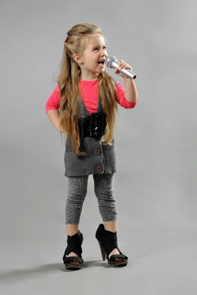 Μικρό κορίτσι τραγουδώντας karaoke σε γκρι φόντο — Φωτογραφία Αρχείου