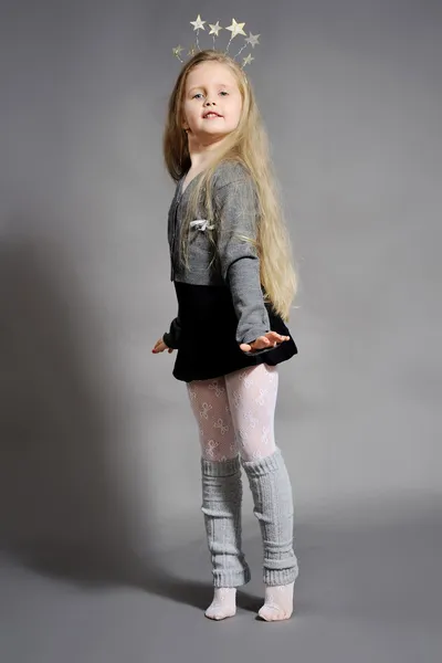 Gri bir arka plan üzerinde yeni yılda giymiş küçük bir kız — Stok fotoğraf
