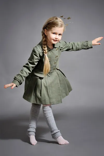 Gri bir arka plan üzerinde yeni yılda giymiş küçük bir kız — Stok fotoğraf