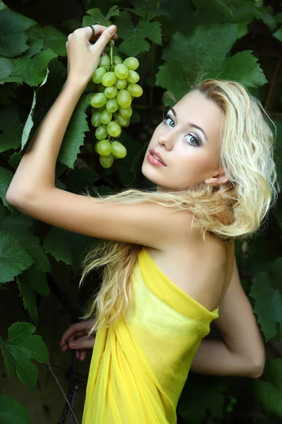 Portret van een mooie jonge blonde met een tros druiven — Stockfoto