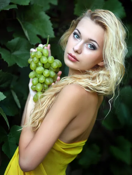 Portrait of a beautiful young blonde with a bunch of grapes — Stock Photo, Image