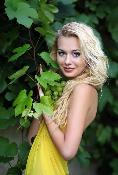 一个美丽的年轻金发女郎与一串葡萄的肖像 — 图库照片