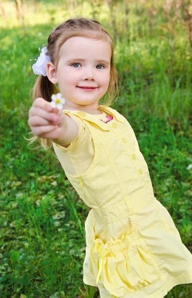 Porträt eines lächelnden süßen kleinen Mädchens, das eine Blume schenkt — Stockfoto