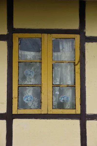 Stock image Yellow latticed window with curtain and brown framework