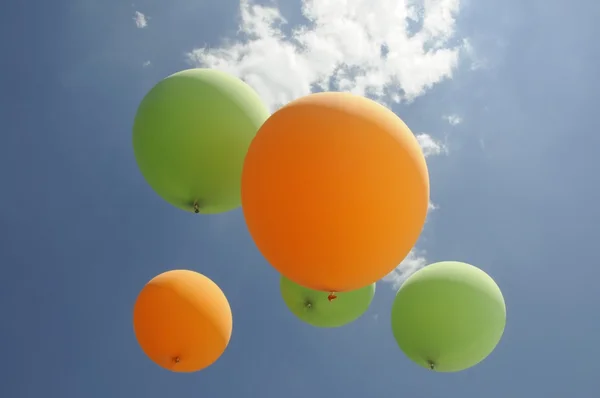 Balões de ar verde e laranja pairam em direção ao sol — Fotografia de Stock