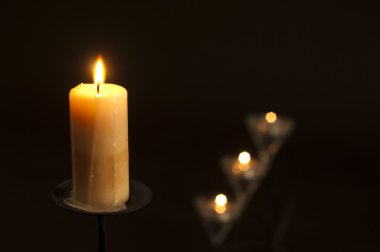 Candles lighting in the darkness with shallow depth of field clipart