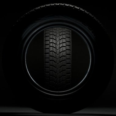 Black winter tire seen through the circle of another winter tire clipart