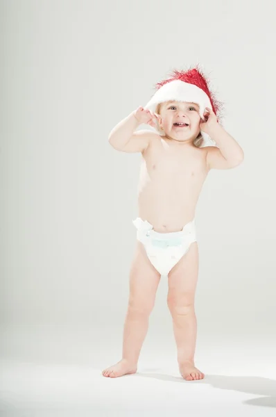 可爱的小宝宝蹒跚学步女孩穿着圣诞老人的帽子和尿布 — 图库照片