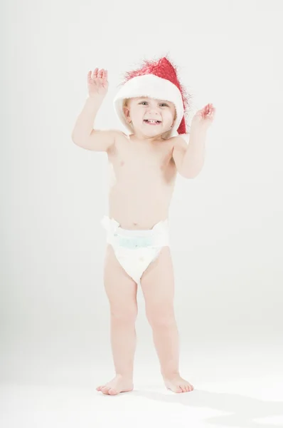 Милая счастливая малышка в шапке Санты и подгузниках — стоковое фото