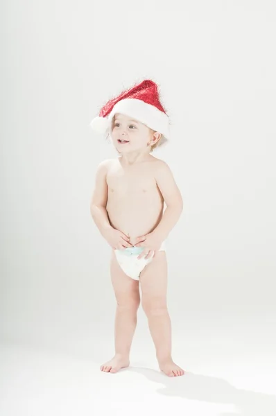 Happy cute baby toddler girl wearing santa's hat and diapers standing — Stock Photo, Image