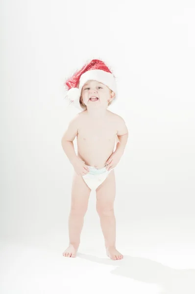 Happy cute baby toddler girl wearing santa 's hat and diapers standing — стоковое фото