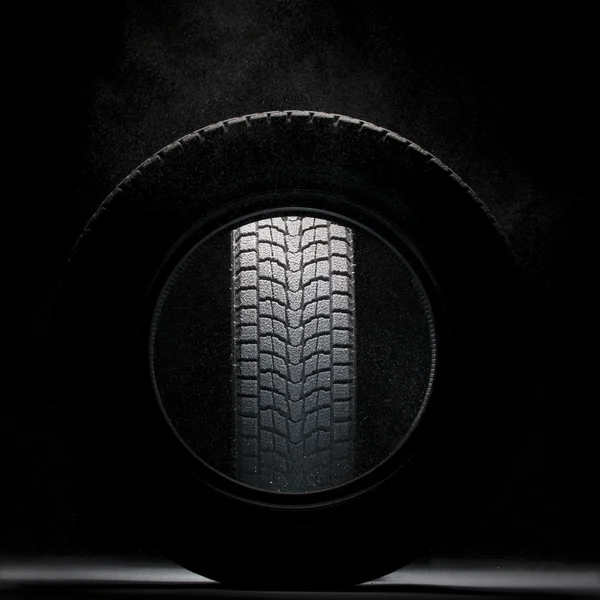 Neumático de invierno nevado negro visto a través del agujero de otro neumático de invierno Imagen de archivo