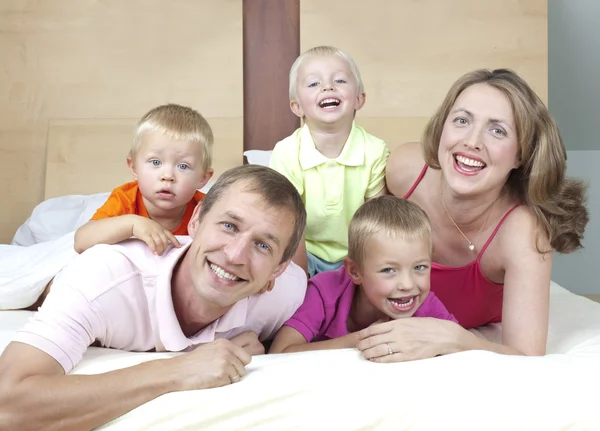Famiglia felice che posa sul letto — Foto Stock
