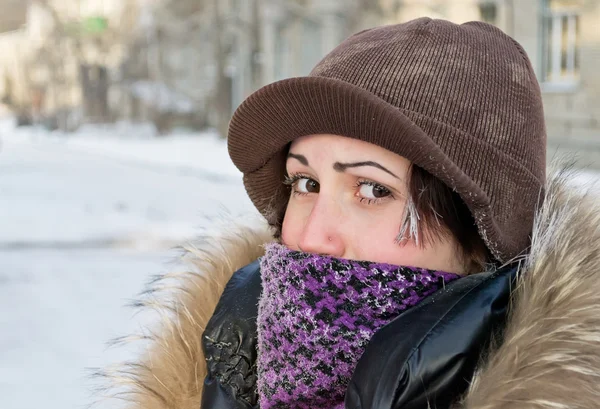Una giovane ragazza per strada, nascosta da una sciarpa, con la palpebra congelata — Foto Stock