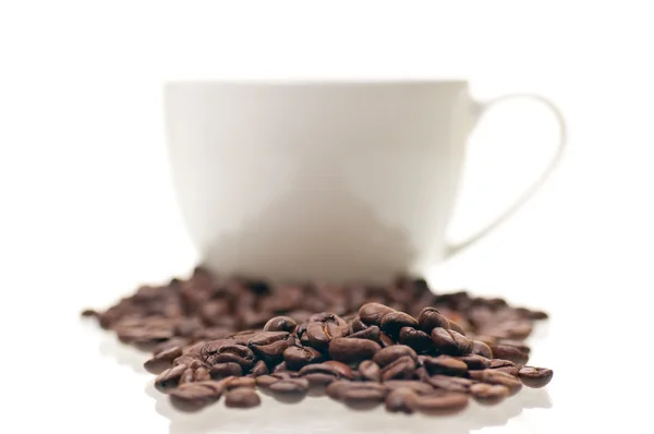 Grano de café de cerca con una taza en el fondo — Foto de Stock