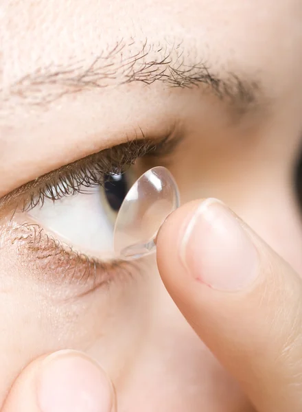 Mujer insertando una lente de contacto en el ojo Fotos de stock